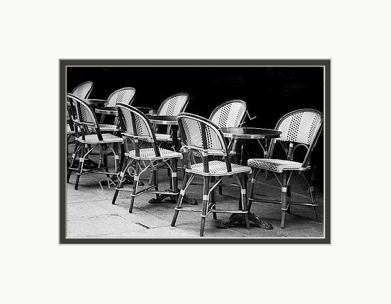 A black and white photograph of cafe table and chairs in the Quartier Latin district in Paris. Shown with a double mount of black on the bottom and white on top.